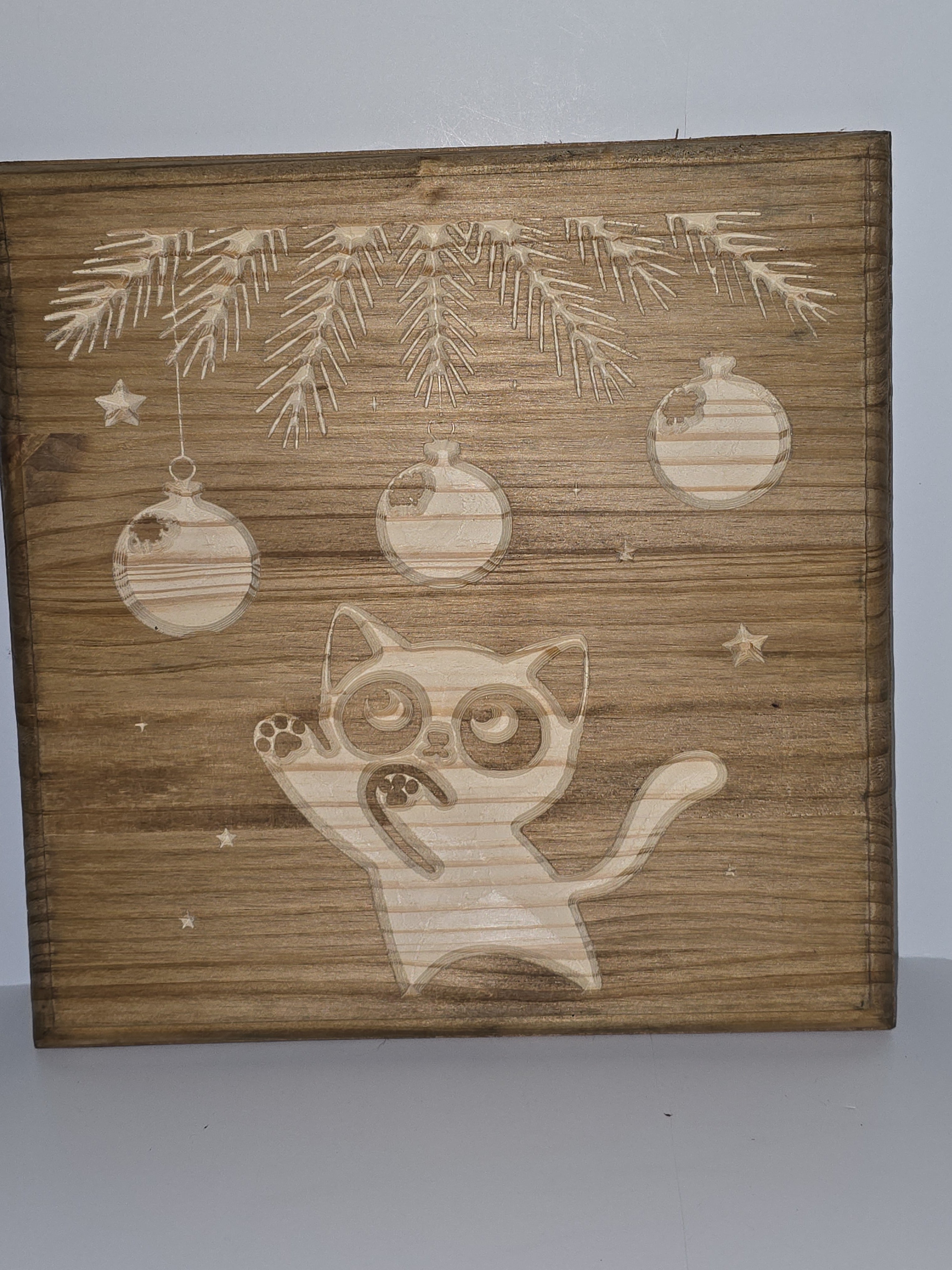 Wooden panel with cnc cut cat and Christmas tree design on a plain background
