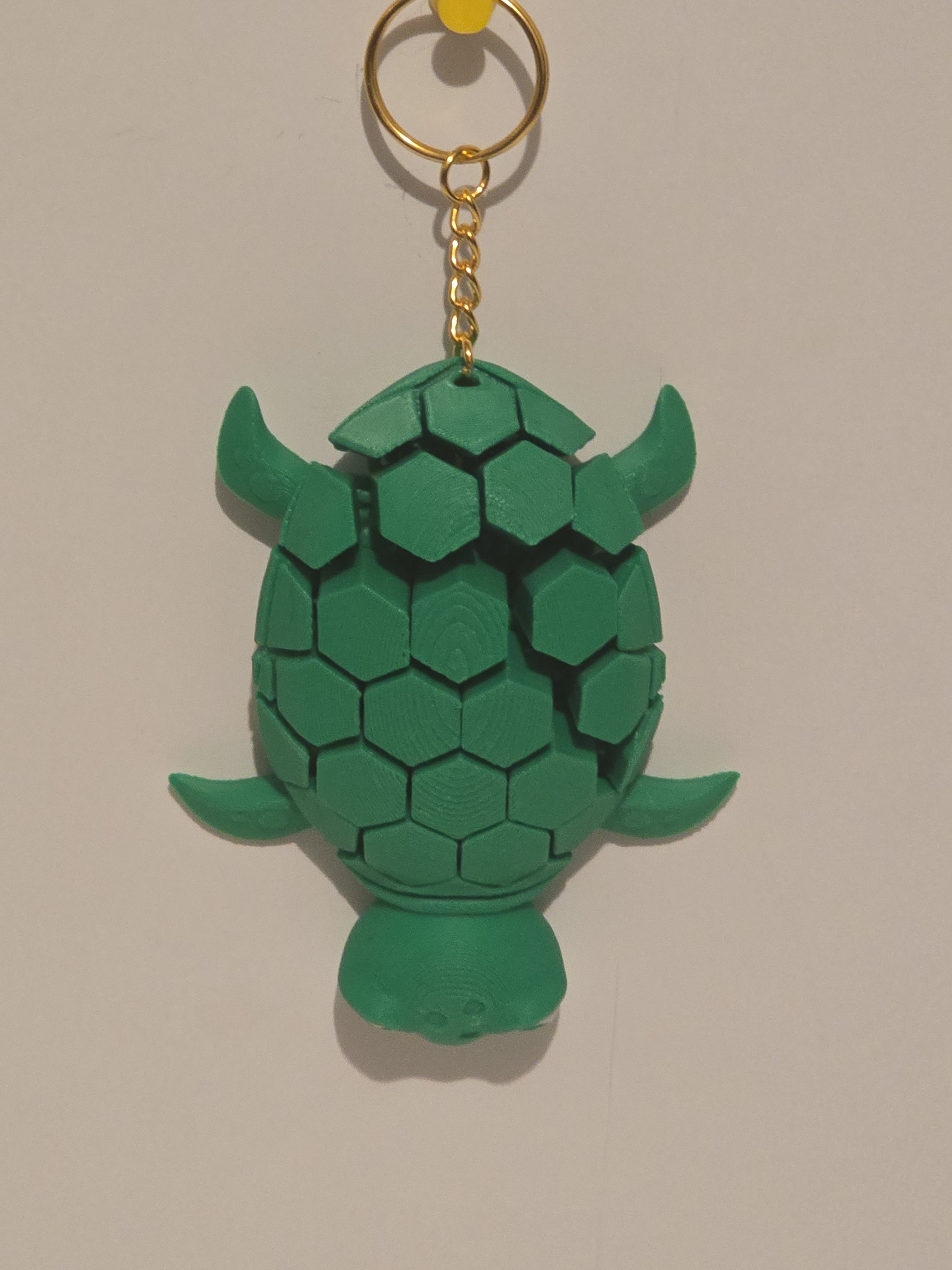 Green turtle-shaped keychain on a beige background