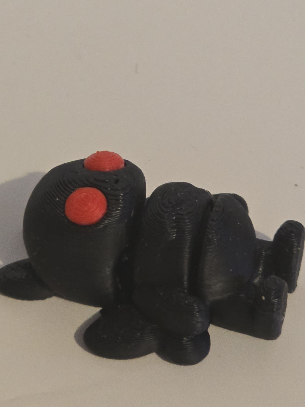 moth man toy figure with red buttons on a light gray background