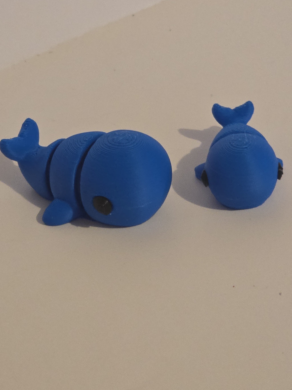 Two blue whale-shaped objects on a beige background