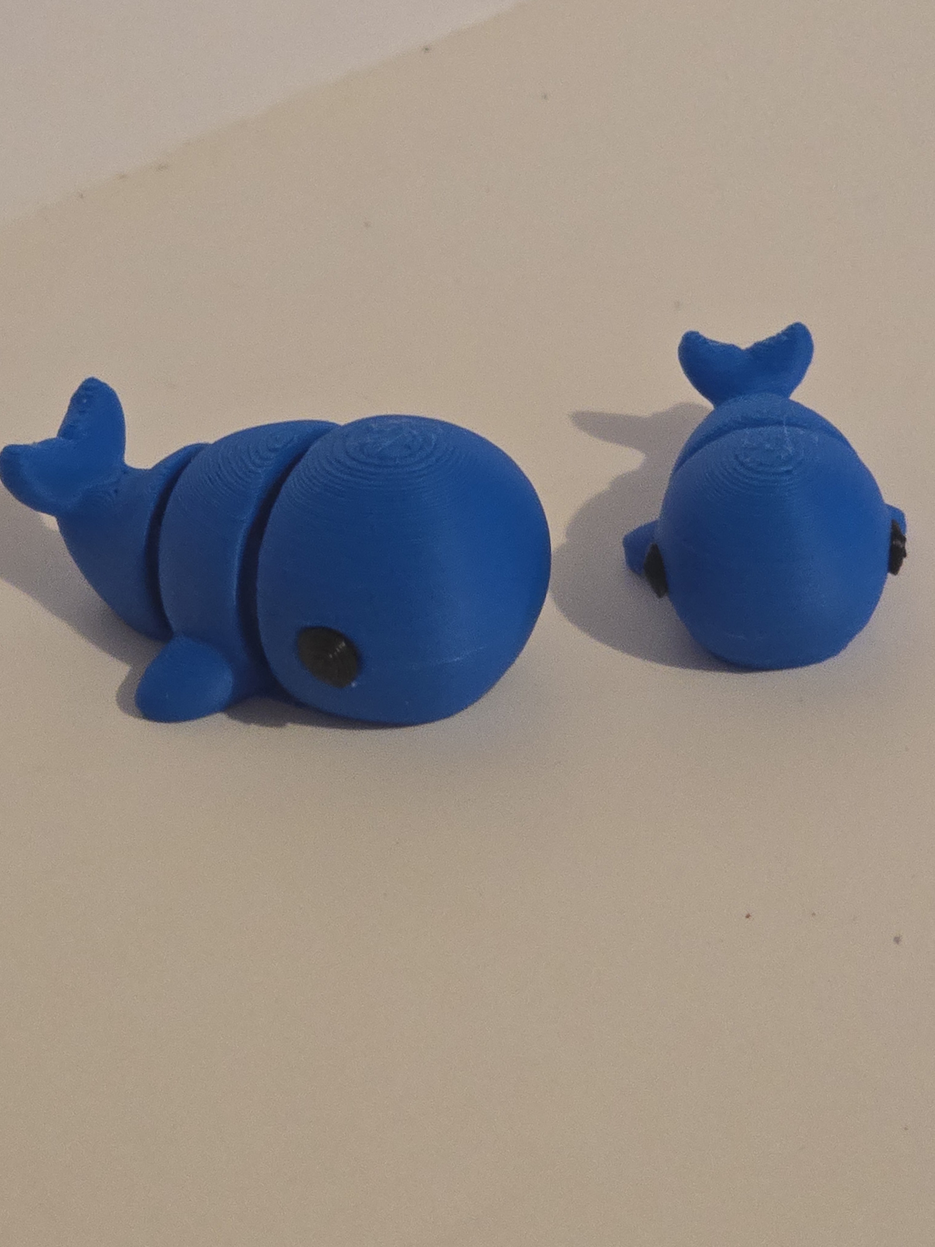 Two blue whale-shaped objects on a beige background