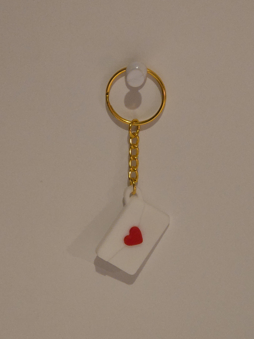 Gold keychain with a heart-shaped tag on a beige background