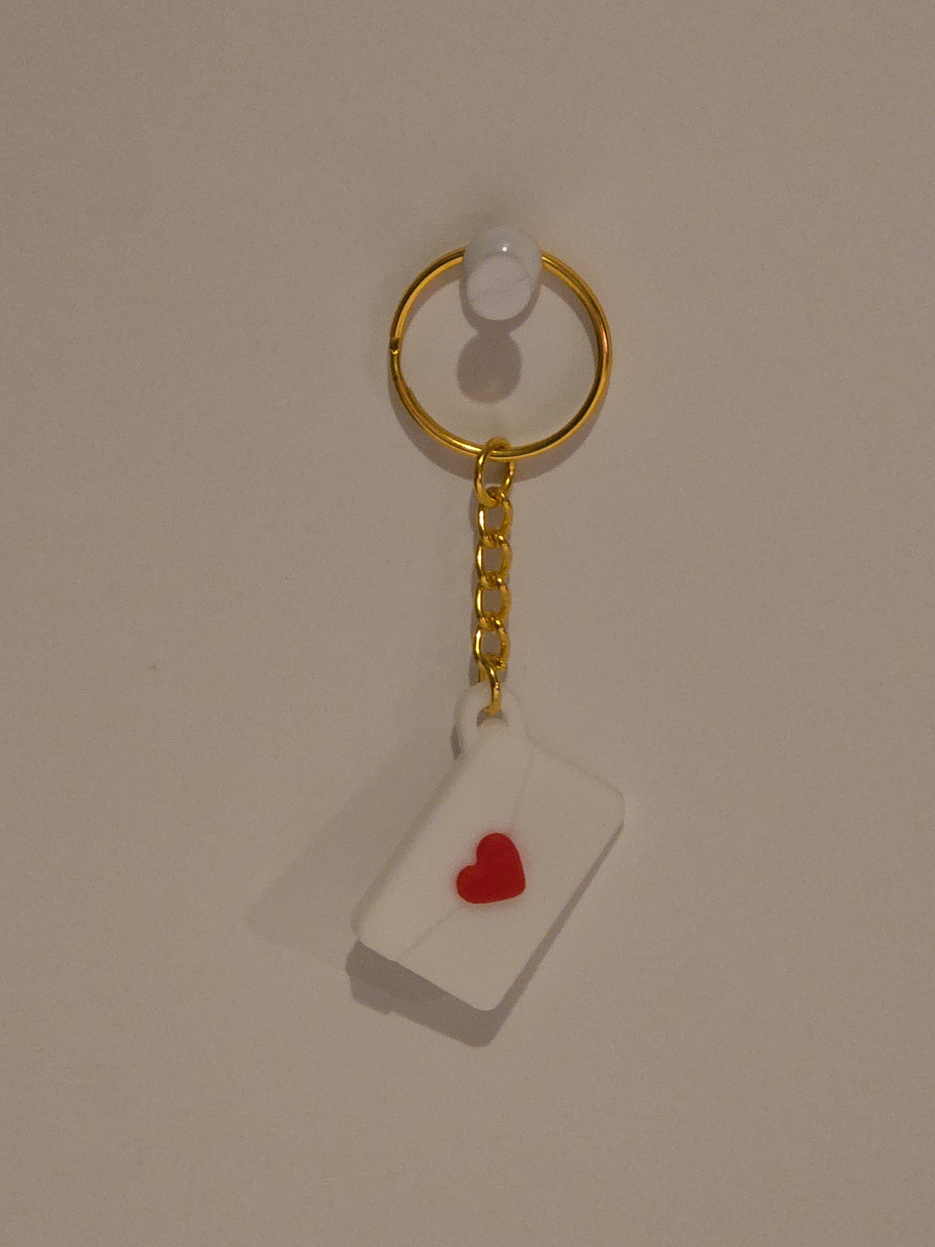 Gold keychain with a heart-shaped tag on a beige background