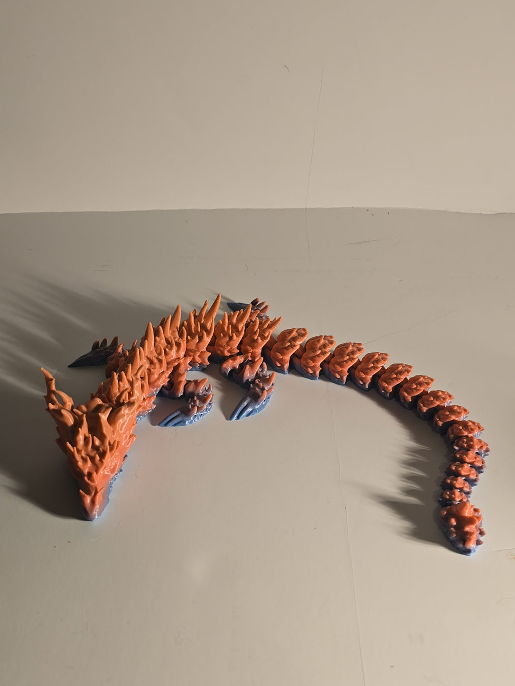 Orange and blue water dragon-like creature toy on a beige background