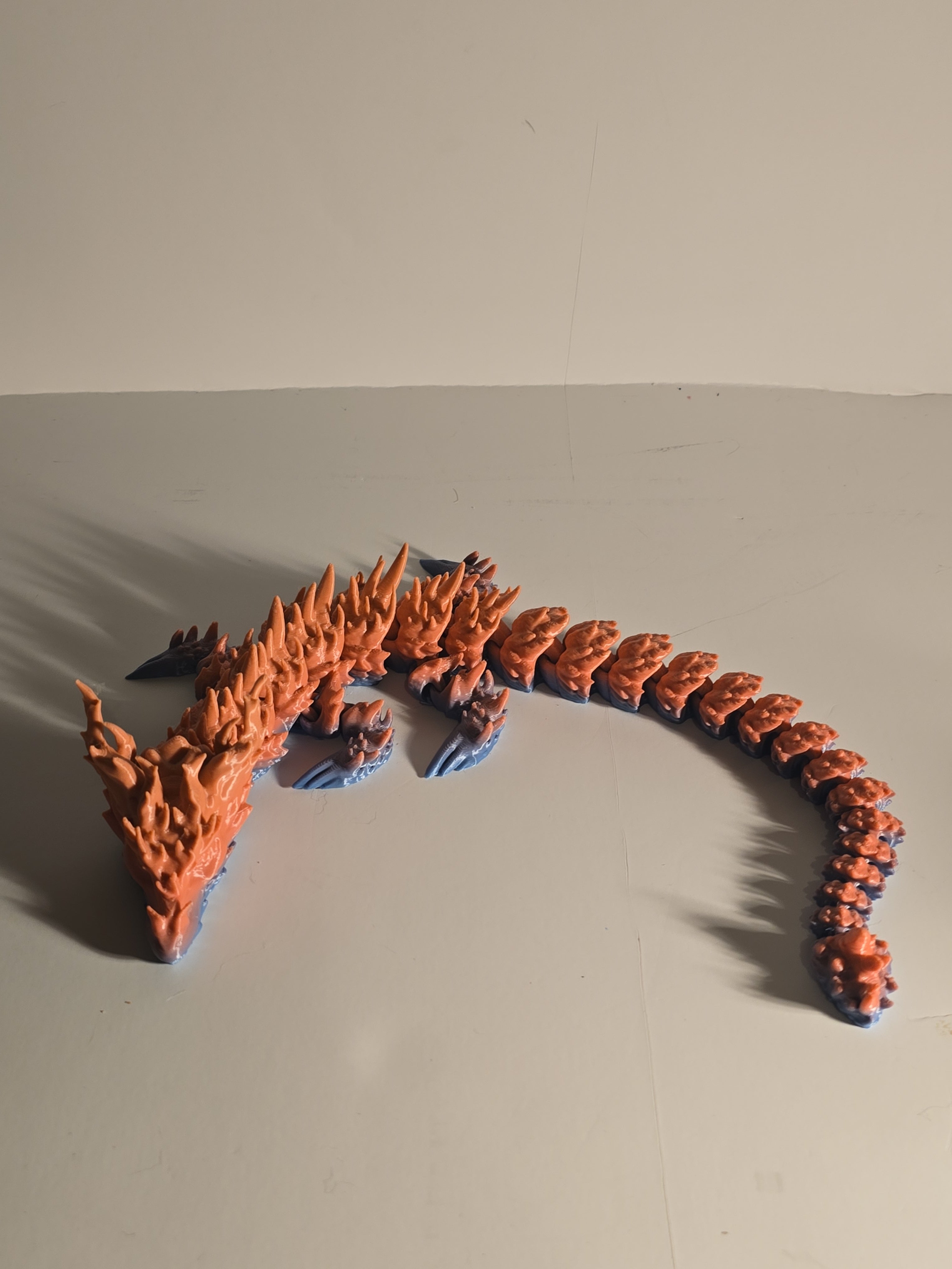 Orange and blue water dragon-like creature toy on a beige background