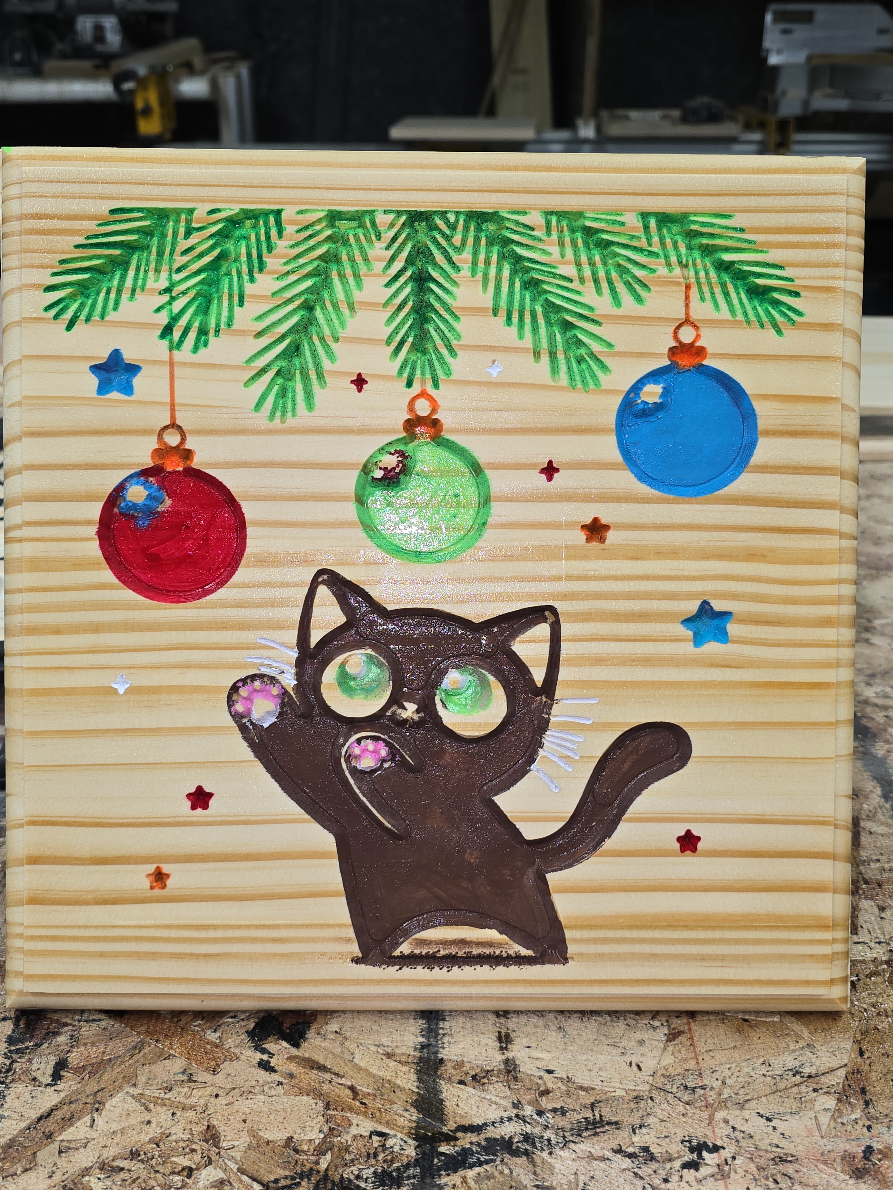 Decorative card with a black cat, Christmas ornaments, and pine branches on a wooden background.