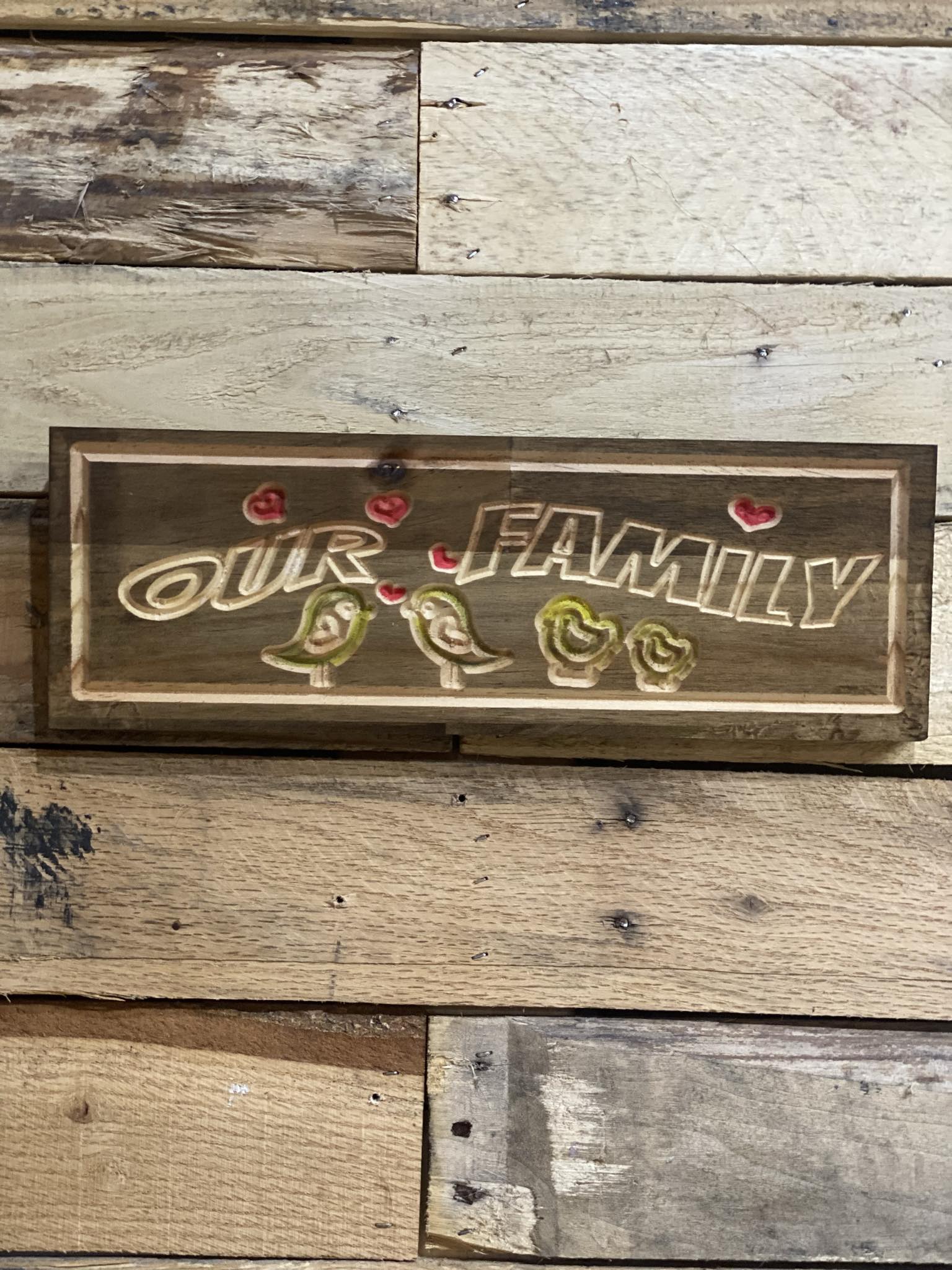Wooden sign with 'Our Family' and bird illustrations on a rustic wooden background