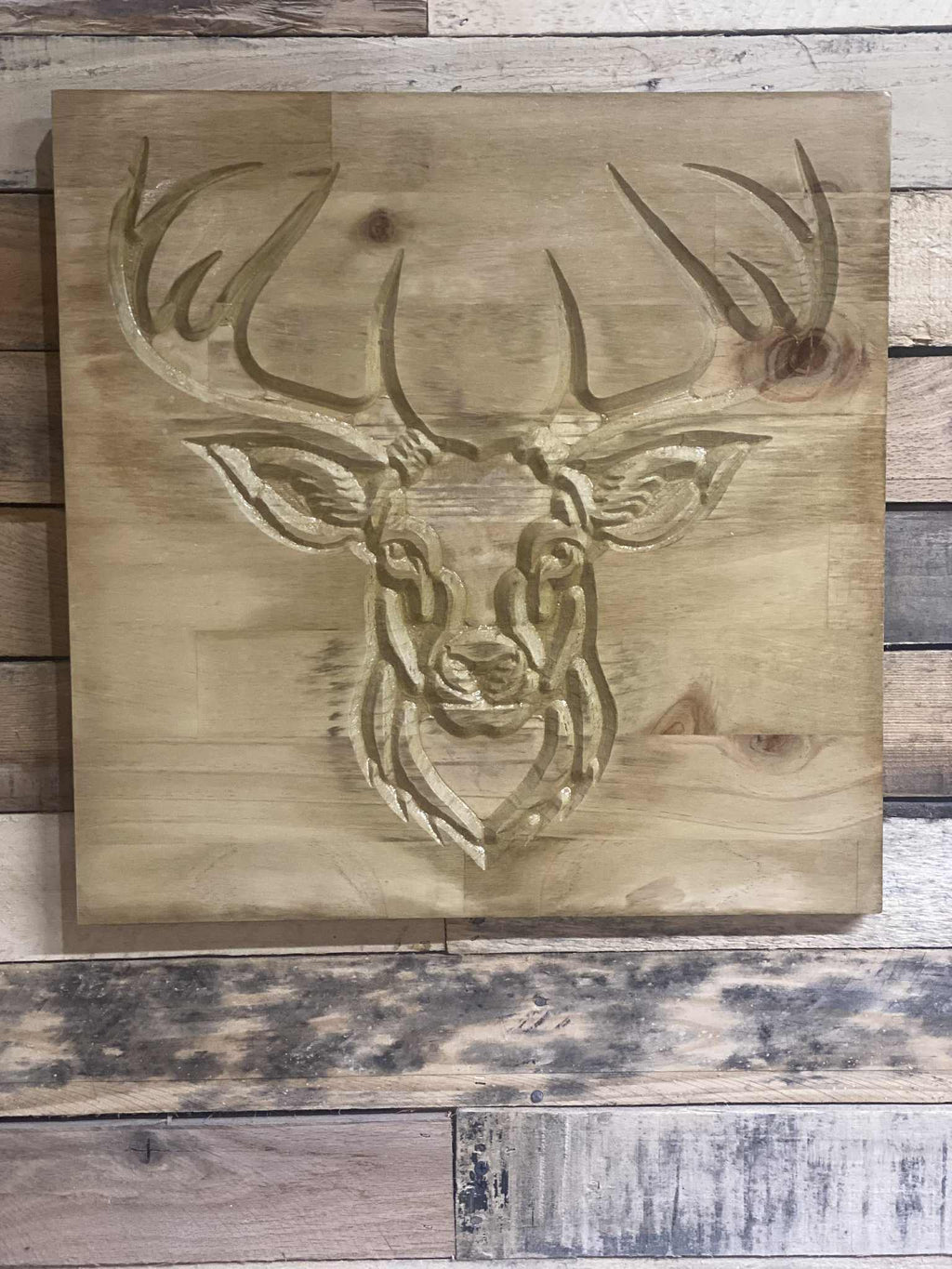 Wooden plaque with a deer head engraving on a rustic wooden background